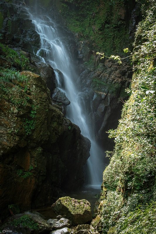 A waterfall pouring down a narrow, moss-covered gorge
