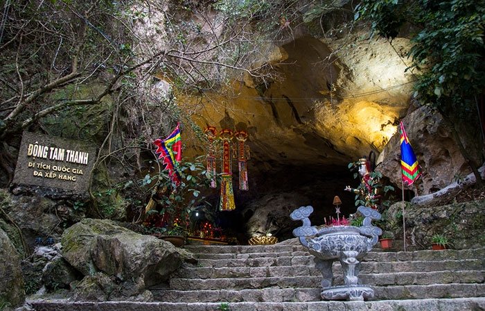 Stone steps leading up to the entrance of Tam Thanh Cave, decorated with flags and an incense urn